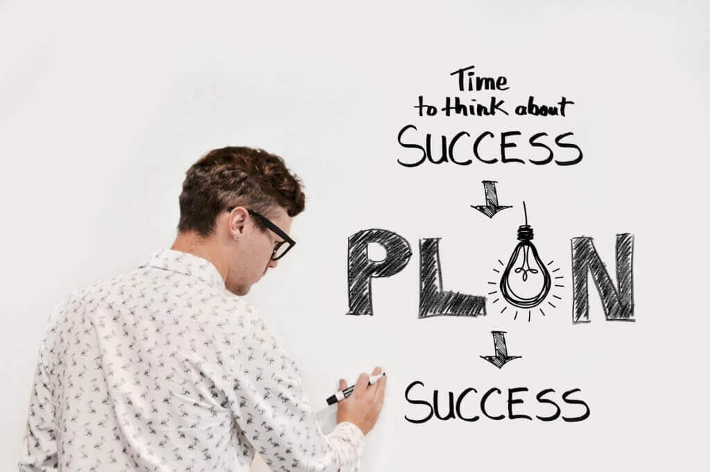 Homme qui dessine pour expliquer que la clé du succès est la planification.